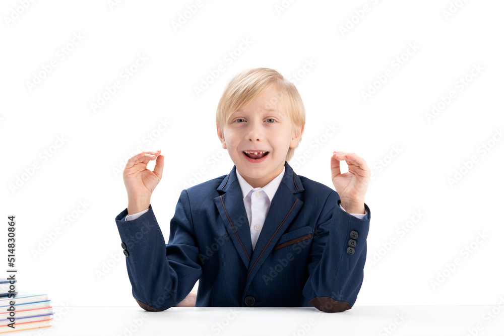 Blond boy in school uniform fools around and laughs. Fidget boy. Portrait of primary school child. White background Blond boy in school uniform fools around and laughs. Fidget boy. Portrait of primary school child. White background