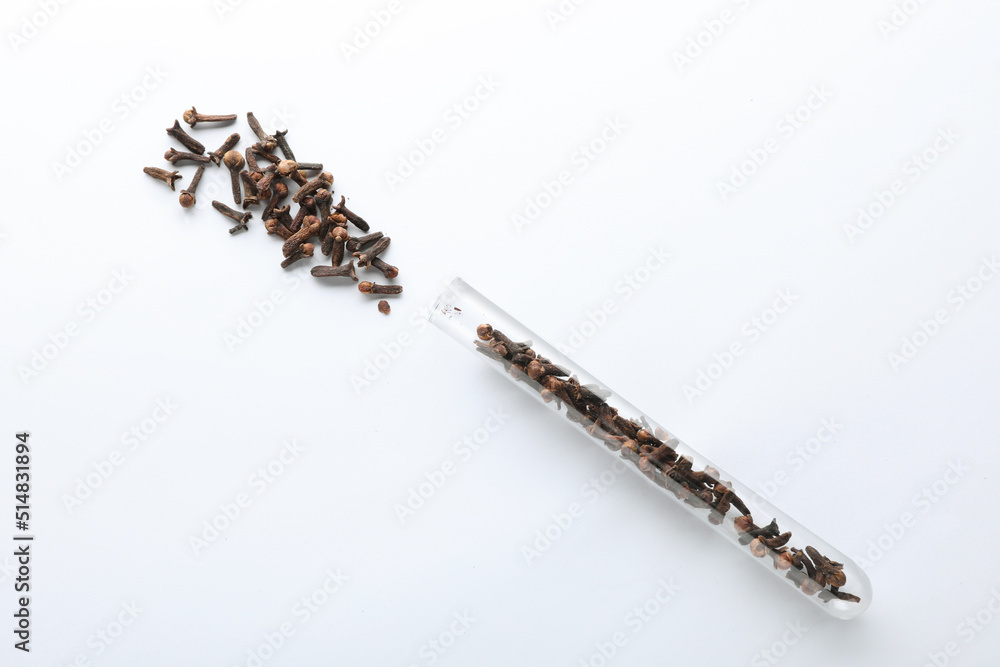 Glass tube with cloves on white background, top view