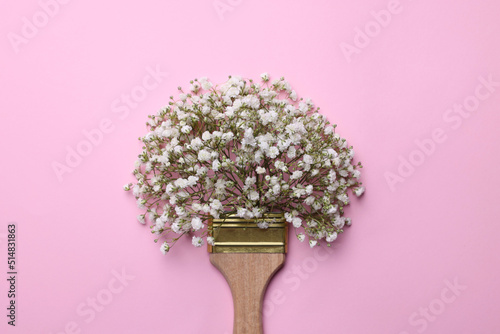 Creative composition with paint brush and gypsophila flowers on pink background, top view