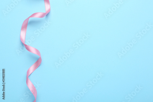 Beautiful pink ribbon on light background, top view. Space for text
