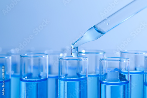 Dripping reagent into test tube on light blue background, closeup. Laboratory analysis