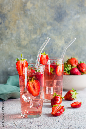 Refreshing cocktail with strawberries in glasses with a straw on the table. Vertical view