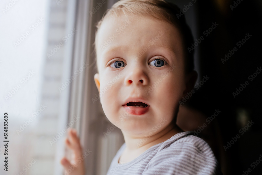 close up portrait of sad little caucasian boy by the window. image with selective focus and toning