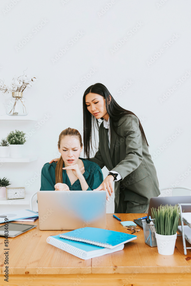 two young business women professionals in formal wear clothes work in modern office using laptop, tablet, brainstorm and search for solutions together, confident independent Asian girl solves problems two young business women professionals in formal wear clothes work in modern office using laptop, tablet, brainstorm and search for solutions together, confident independent Asian girl solves problems