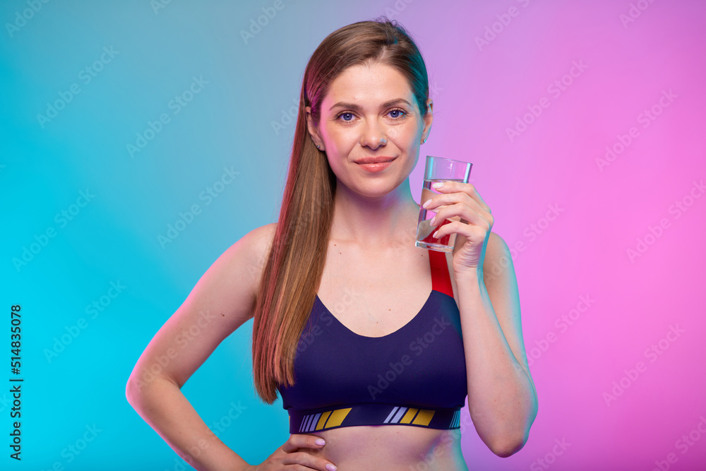 Smiling girl holding water glass. Female fitness portrait isolated on neon color background. Smiling girl holding water glass. Female fitness portrait isolated on neon color background.