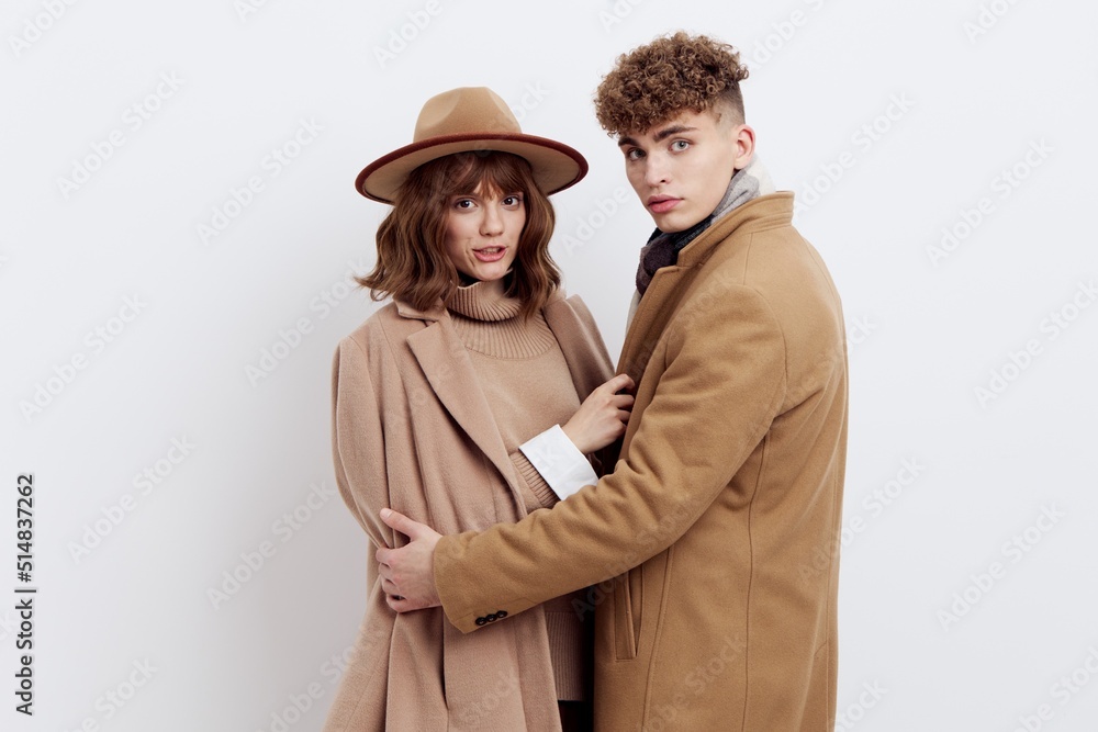 a sweet, beautiful, loving couple stands on a white background in stylish autumn clothes, a woman has a hat on her head, and she gently snuggles up to a man looking into the camera a sweet, beautiful, loving couple stands on a white background in stylish autumn clothes, a woman has a hat on her head, and she gently snuggles up to a man looking into the camera