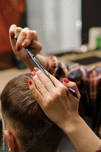 Barbershop, close-up: woman hairdresser cuts hair, makes a man's haircut