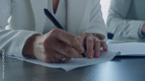 Closeup hand holding pen. Divorcing woman signing documents in attorney office.  photo