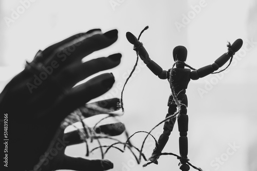 Wooden puppet tied with ropes to the puppeteer, manipulation of people, people are slaves, propaganda