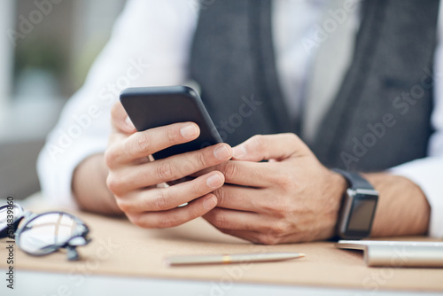 Close-up of unrecognizable businessman sitting at table and using mobile internet on smartphone