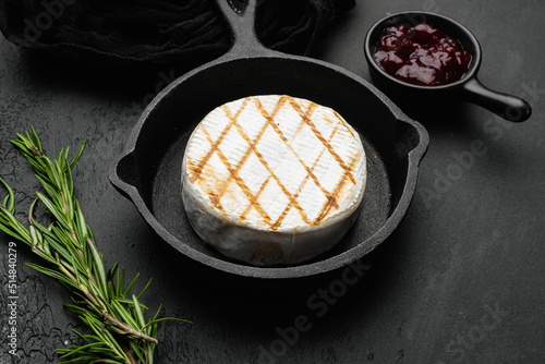 Baked Camembert cheese on black dark stone table background