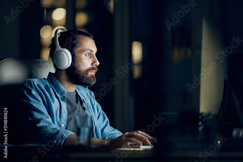 Wallpaper Mural Focused hipster young man with beard sitting at table and listening to audio whi