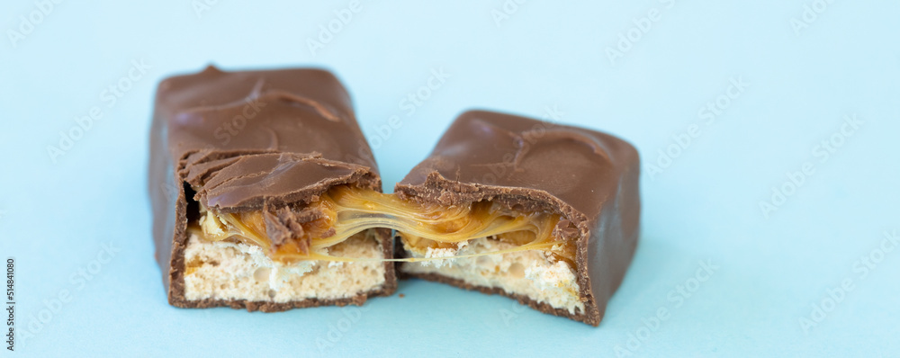 Cracked chocolate bar with caramel on blue background