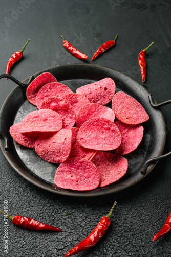 Hot Flavored Potato Chips on black dark stone table background