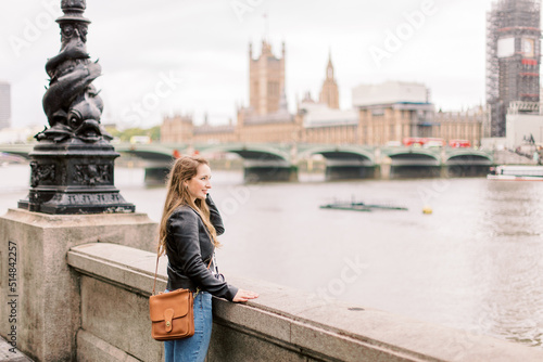 Photography A Caucasian beautiful woman in front of the River Thames  in London, Great Britain with Palace of Westminster and chapel in the background