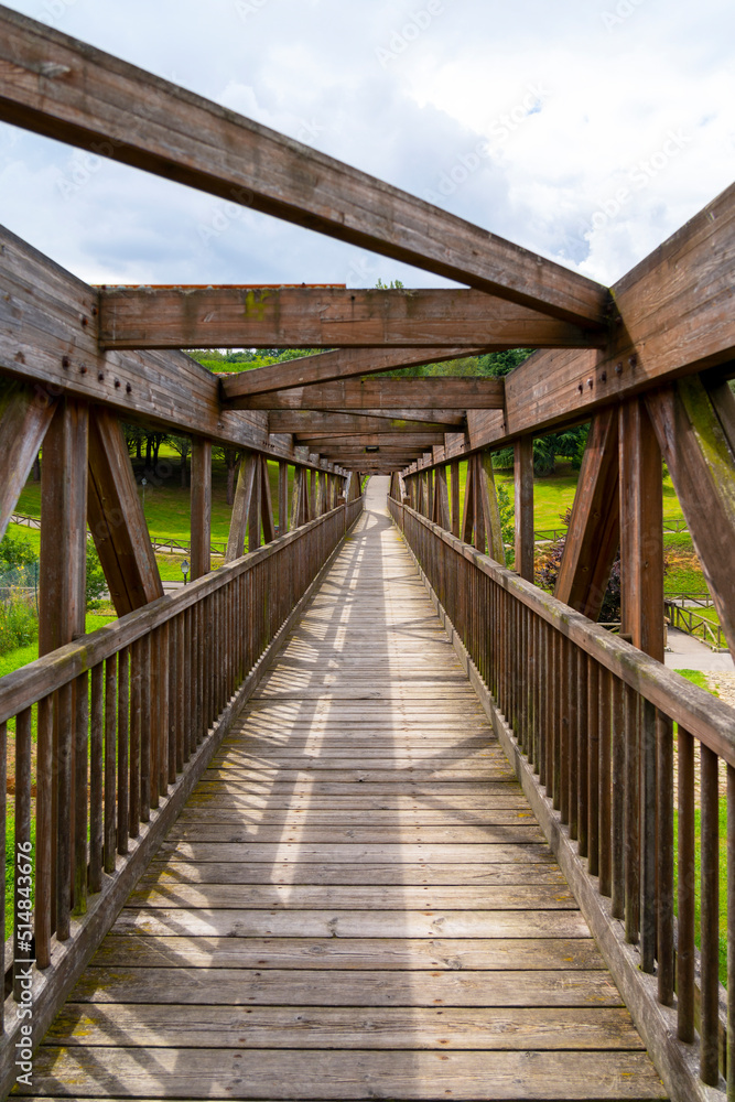 Wooden bridge with boardwalk and crossing beams. Footbridge with geometric perspective