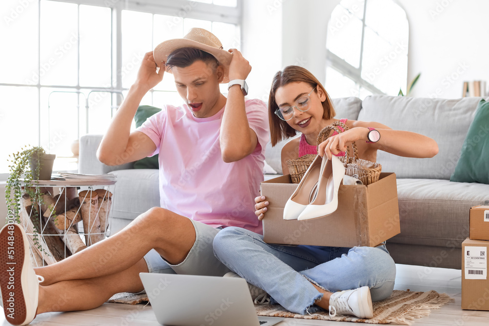 Young couple unpacking box with new clothes at home. Online shopping