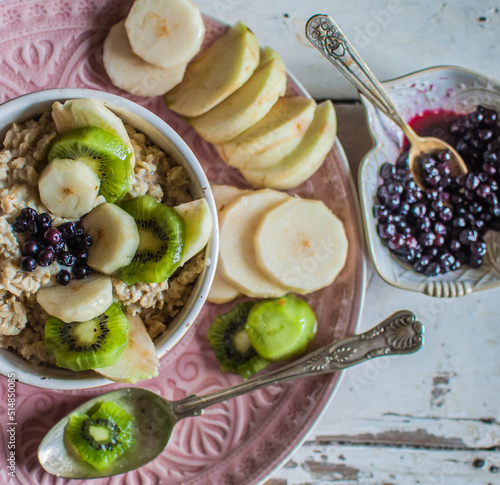 oatmeal with fruits, healthy breakfast on pink plate, blueberries,