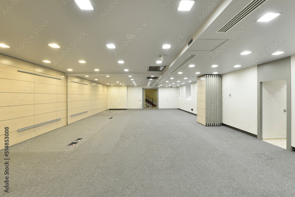 Large room to dedicate to empty offices, with floors covered with gray carpet and folding screens in the middle of the room