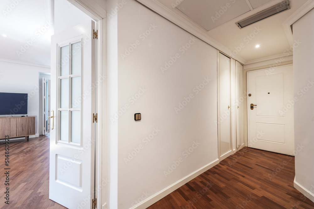 Fototapeta premium Entrance hall and corridor of a house with dark parquet floors, plain white painted walls and white lacquered wood carpentry