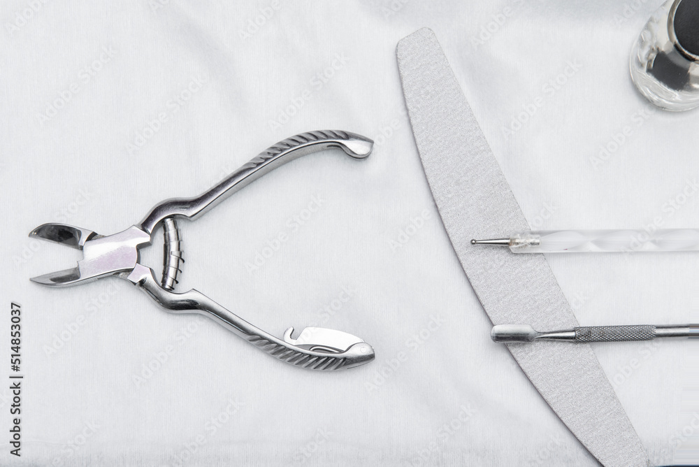 Chrome metal tongs next to nail file and other utensils for grooming hands Chrome metal tongs next to nail file and other utensils for grooming hands