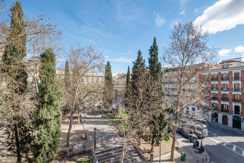 A Madrid square with many trees and a predominantly clear sky A Madrid square with many trees and a predominantly clear sky