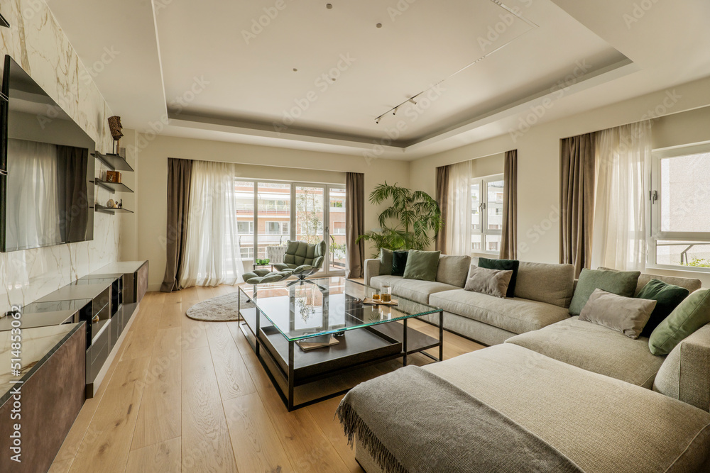 Fototapeta premium living room with sofas and a large glass top side table and windows leading out to a terrace in a luxury home