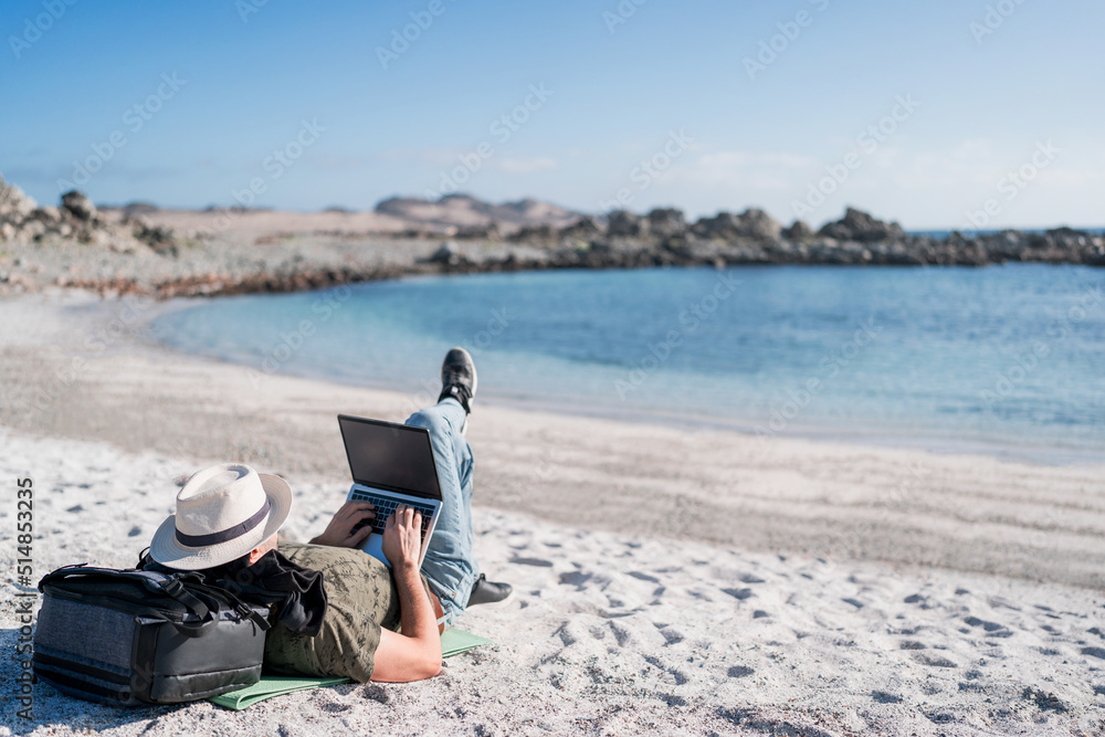 digital nomad lying on the beach outdoors alone working relaxed.