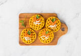 Round carrot waffles on a wooden board. Light background. Top view