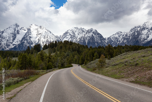 Scenic Road surrounded by Mountains and trees in American Landscape. Spring Season. Grand Teton National Park. Wyoming, United States. Nature Background.