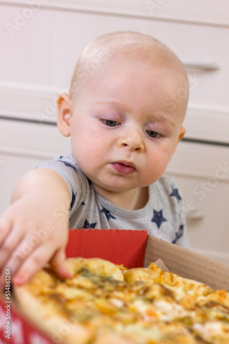 Cute little kid boy taking a slice of pizza.