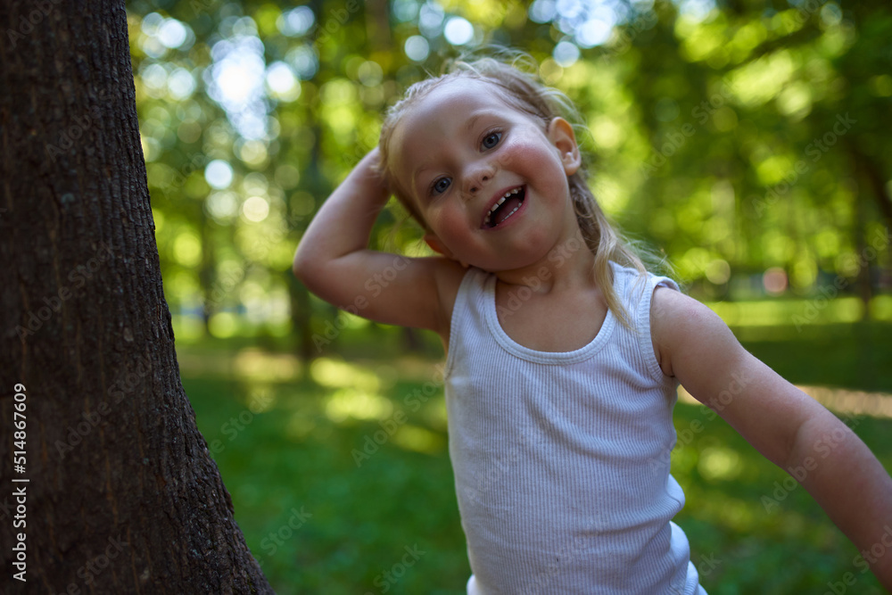 a child in the woods shows positive emotions standing next to a large tree a child in the woods shows positive emotions standing next to a large tree