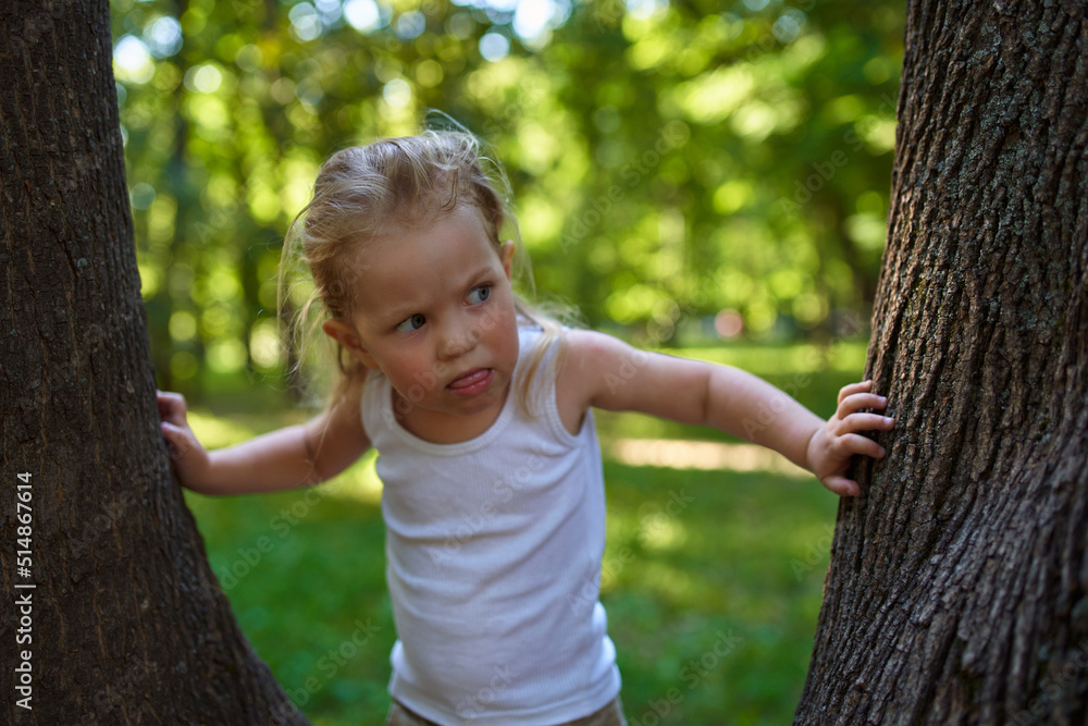 a child in the woods shows positive emotions standing next to a large tree a child in the woods shows positive emotions standing next to a large tree