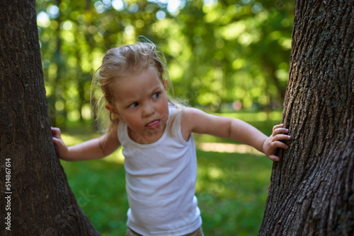 a child in the woods shows positive emotions standing next to a large tree