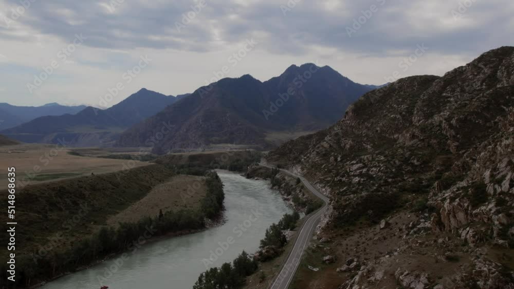 Mountains valley of Altai with blue Katun river under dramatic sky, Siberia, Russia. Beautiful summer nature landscape at during daytime. Aerial view from a drone Mountains valley of Altai with blue Katun river under dramatic sky, Siberia, Russia. Beautiful summer nature landscape at during daytime. Aerial view from a drone