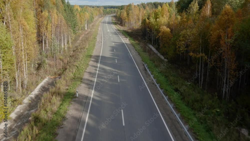 Asphalt road with traffic cars between forest in Ural, Russia. Beautiful autumn nature landscape at during daytime. Aerial view from a drone Asphalt road with traffic cars between forest in Ural, Russia. Beautiful autumn nature landscape at during daytime. Aerial view from a drone