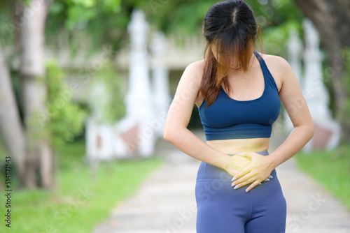 Sporty young woman unhappy unwell sick ill woman hold hand on stomach suffers pain. 