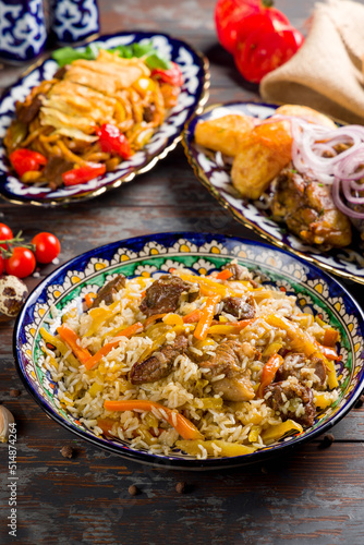 dishes of Uzbek cuisine lagman  pilaf and kazan kebab on wooden table  vertical