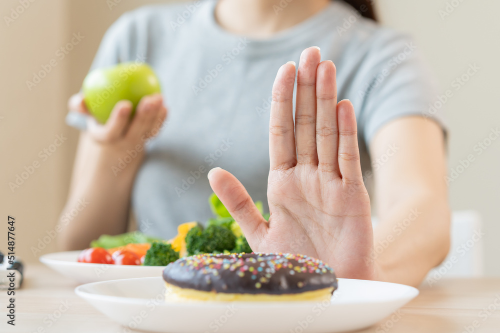 Diet, Dieting asian young woman or girl use hand push out, deny sweet donut and choose green salad vegetables, eat food for good healthy, health when hungry. Close up female weight loss person. Diet, Dieting asian young woman or girl use hand push out, deny sweet donut and choose green salad vegetables, eat food for good healthy, health when hungry. Close up female weight loss person.