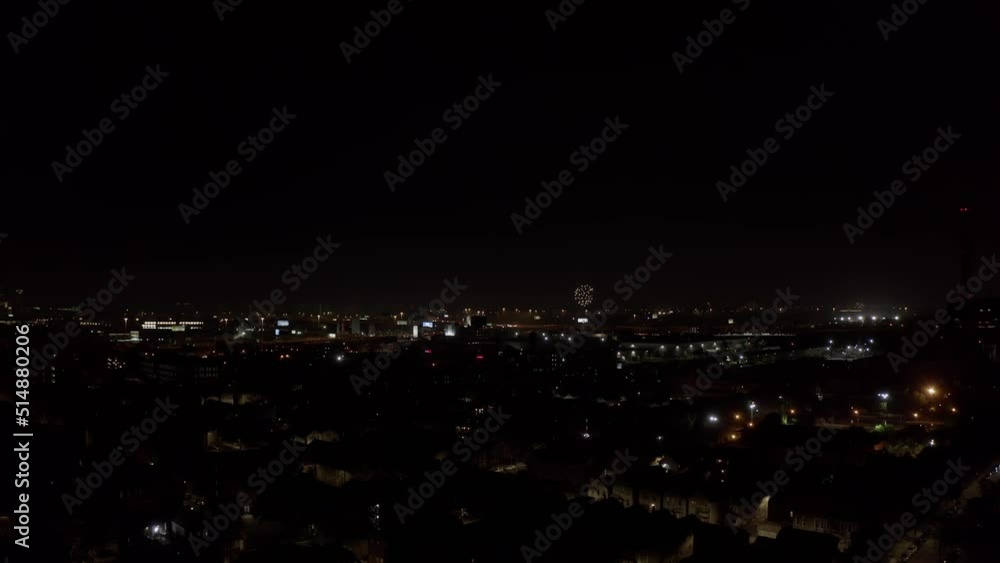 Red flares are set off from a Chicago residential area as large explosions appear on the horizon on a clear Independence day night. Drone lifting night shot Red flares are set off from a Chicago residential area as large explosions appear on the horizon on a clear Independence day night. Drone lifting night shot