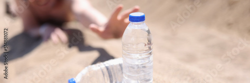 Canvas Print A man in the desert stretches on the sand for bottles of water
