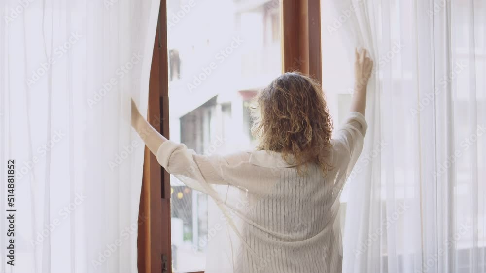 beautiful woman happy smiling in holiday at window curtains. young woman getting up in morning at home and looking outside beautiful woman happy smiling in holiday at window curtains. young woman getting up in morning at home and looking outside