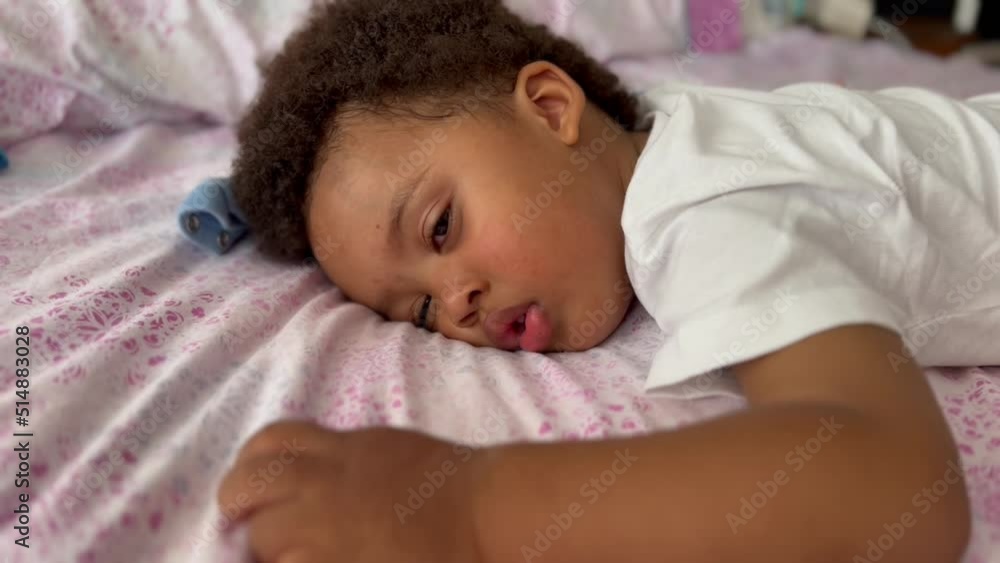 Cute and exotic afro european two year old child awakening from a summer nap in his bed. Cute and exotic afro european two year old child awakening from a summer nap in his bed.