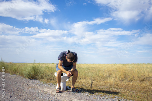 Fotografie a man is sitting on the toilet in a field