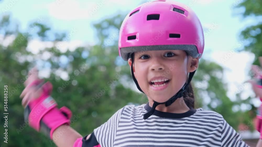 Portrait of a smiling little girl in a helmet learning to skate. Cute little girl practicing roller skating at the park. Exciting outdoor activities for kids Portrait of a smiling little girl in a helmet learning to skate. Cute little girl practicing roller skating at the park. Exciting outdoor activities for kids