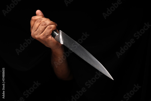 Asian male dark skinned single hand fist finger on black background holding stainless steel knife