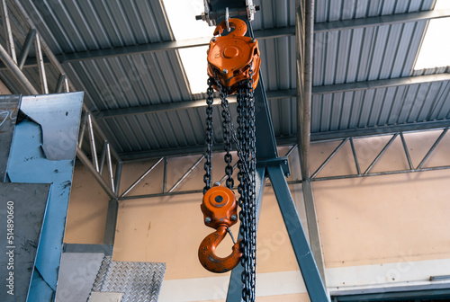 The construction crane in factory. chain hoist hanging on steel box photo