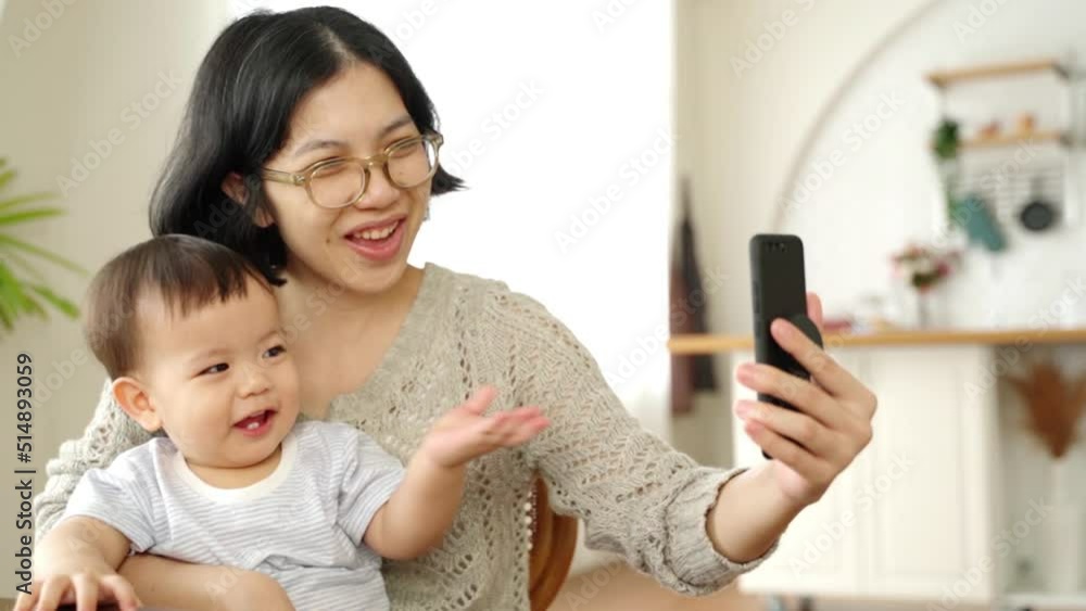 Happy Smiling Asian Young mother and her little son using smartphone at home, taking selfie, Video call. Happy Smiling Asian Young mother and her little son using smartphone at home, taking selfie, Video call.