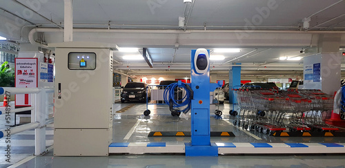 Bangkok, Thailand - March 25, 2022: Blue charging points station for electric car with charger and wire in parking at department store. Technology and Clean energy concept