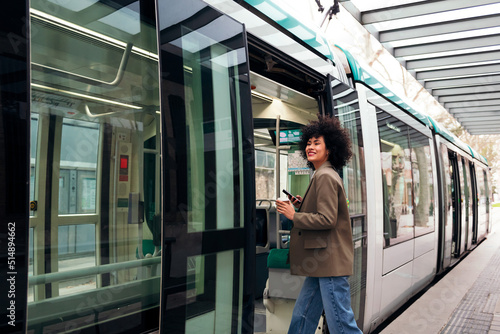 smiling young business woman entering the tram, concept of public transport and urban lifestyle